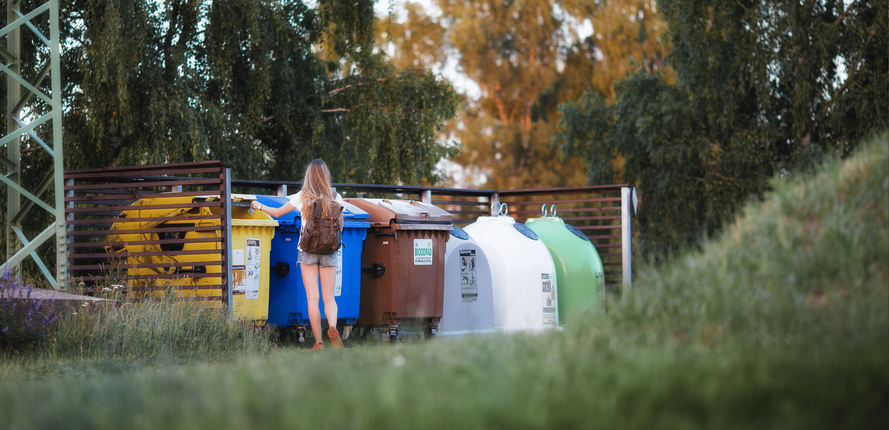A girl throwing trash into a trash can.